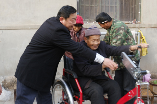 图为滕州市残联领导教陈培良正确使用“手摇三轮车”