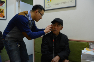 图为验配师在为受助者调试助听器