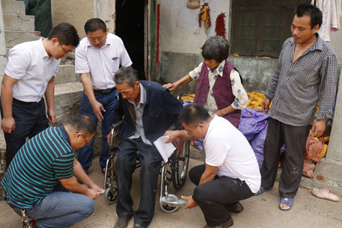 图为滕州市残联工作人员为结对帮扶残疾人送轮椅