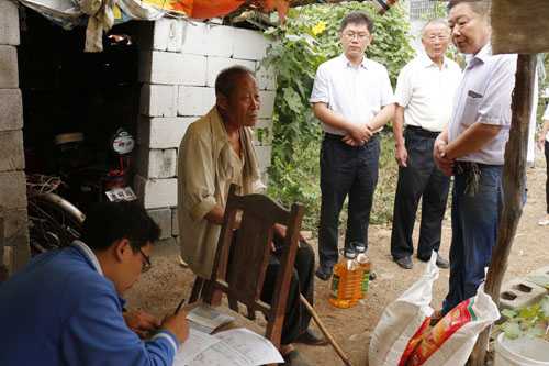 图为滕州市残联工作人员正在为结对帮扶贫困户现场办理残疾人证