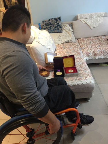 图为刘磊向采访组展示蝉联三连冠奥运金牌