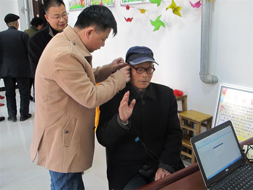 图为：技术人员为听障残疾人验配助听器