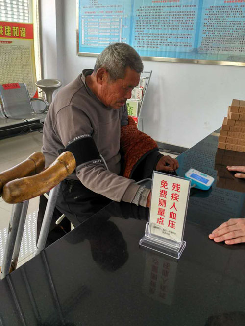 图为残疾人在峄城区阴平镇残联免费测压点测量血压