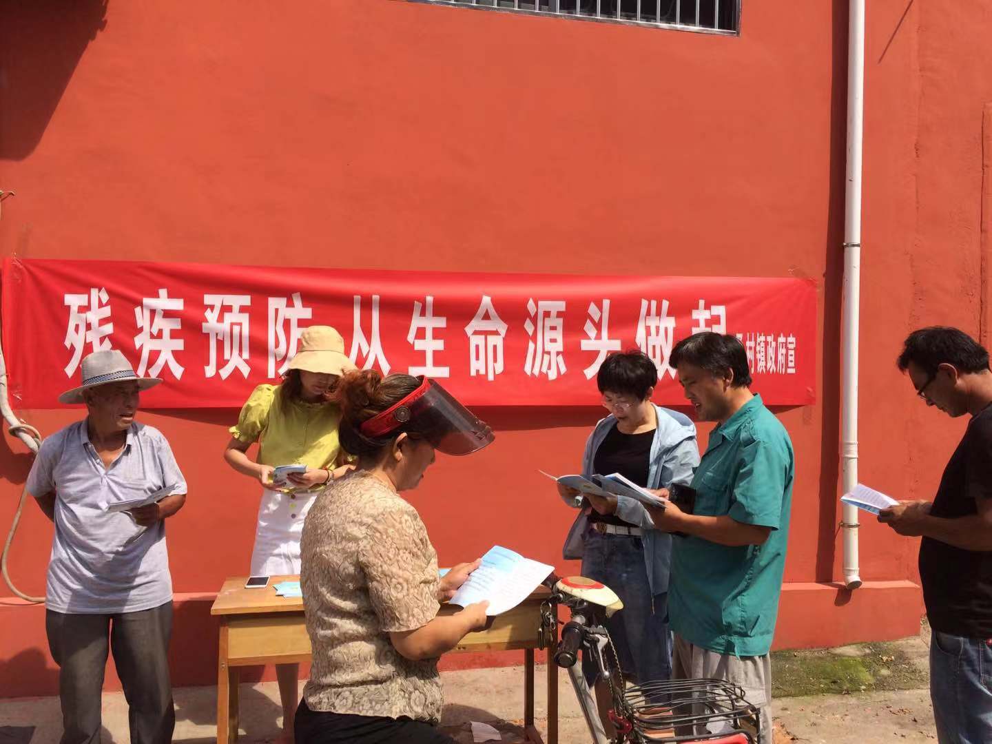图为工作人员向居民发放宣传材料并了解残疾预防相关知识。