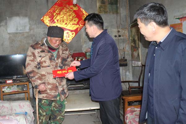 图为祝世峰理事长为姜屯镇贫困残疾人送上慰问金。
