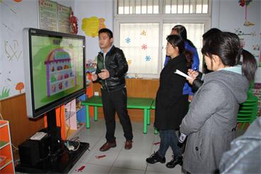 图为教师们在仔细观看技术人员对听力语言康复多媒体互动教学系统的操作演示