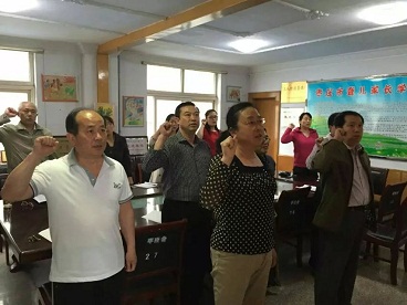 图为鲜红的党旗下，新党员入党宣誓、老党员重温入党誓词。