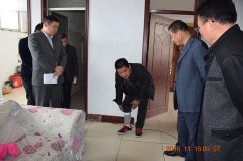图为检查组在底阁肢体残疾人季德华家中检查热力器及扶梯改造项目