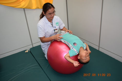 图为脑瘫儿童康复治疗师张喆在帮助脑瘫儿童进行pt训练