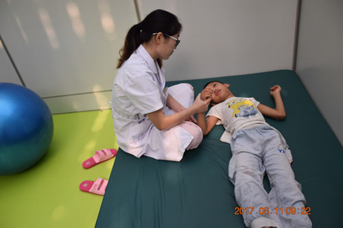 图为脑瘫儿童康复治疗师付瑶在帮助脑瘫儿童进行pt训练2