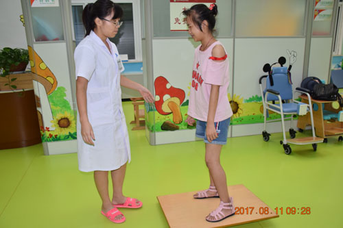 图为脑瘫儿童康复治疗师叶梅聆在帮助脑瘫儿童进行pt训练1
